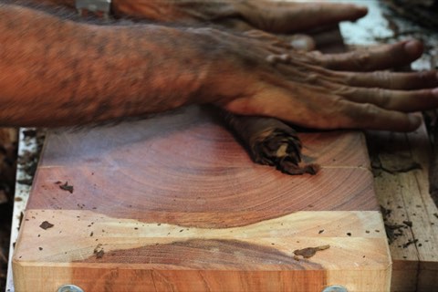 Hands rolling a cigar on the cedar board
