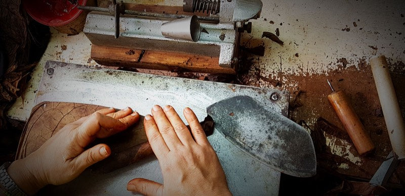 A cigar taking shape at the rolling bench beside the chaveta blade