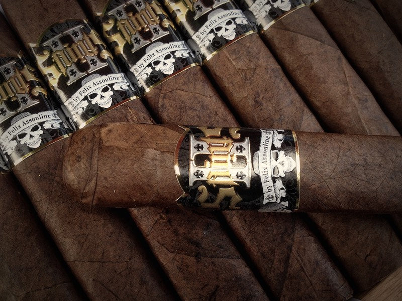 II Saints cigars with black, white and gold bands, laid across the box